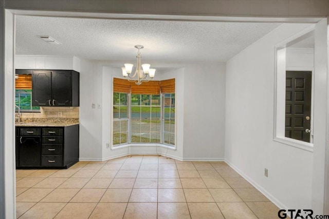 unfurnished dining area with visible vents, light tile patterned flooring, baseboards, a textured ceiling, and a chandelier