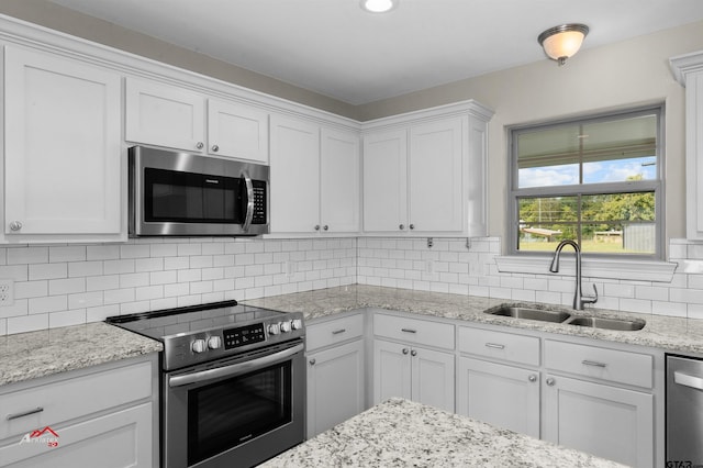 108 Benny St, Longview, TX 75604 - kitchen with appliances with stainless steel finishes, a sink, white cabinets, backsplash, and light stone countertops