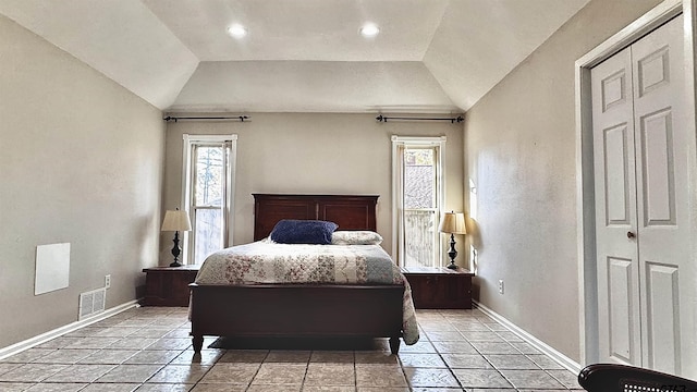 bedroom with lofted ceiling, multiple windows, and a closet