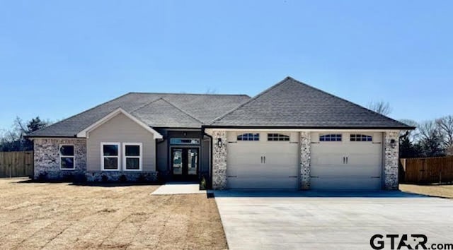 view of front of property with concrete driveway, fence, a garage, and french doors