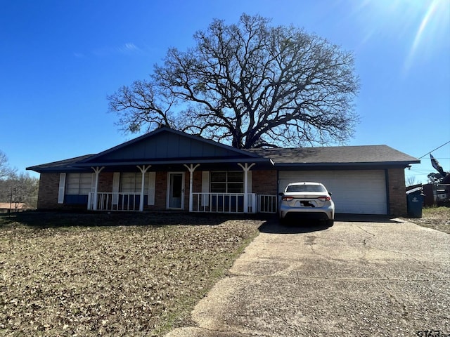 view of front of house featuring brick siding, board and batten siding, a porch, a garage, and driveway
