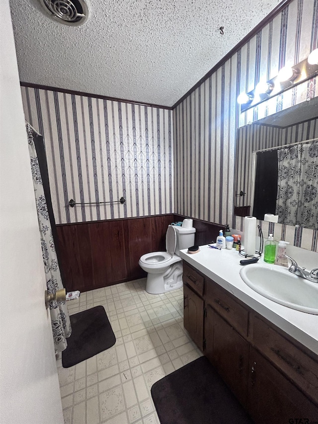 full bathroom featuring vanity, a shower with curtain, wallpapered walls, a textured ceiling, and toilet