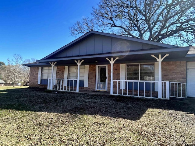 ranch-style house with brick siding, covered porch, board and batten siding, and a garage