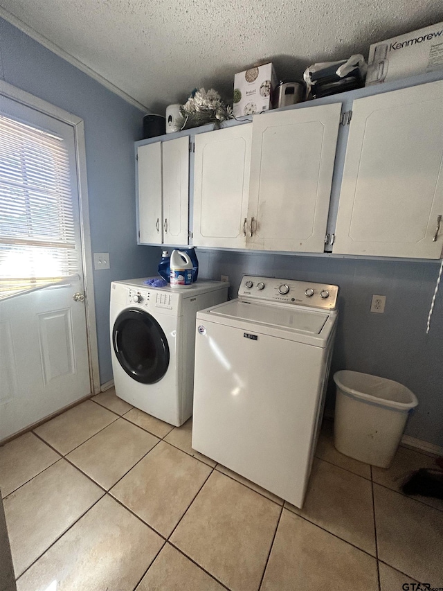 washroom featuring cabinet space, a textured ceiling, independent washer and dryer, and light tile patterned flooring