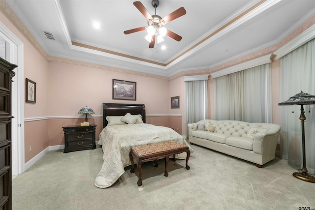 bedroom with a tray ceiling, light colored carpet, ceiling fan, and crown molding