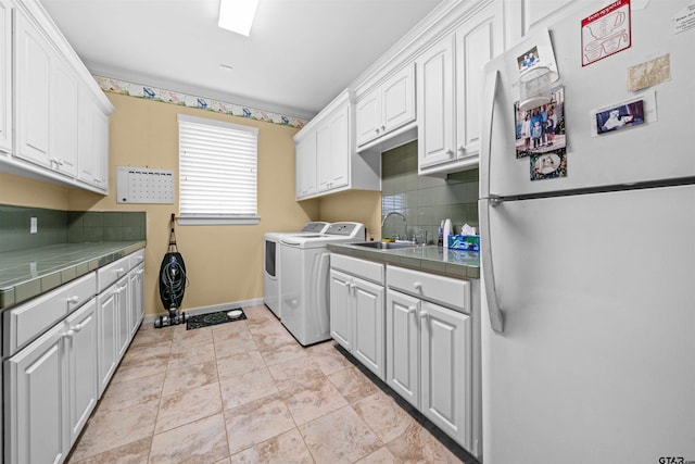 clothes washing area featuring cabinets, sink, and independent washer and dryer