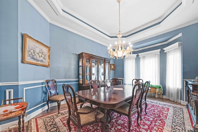 dining space with ornamental molding, hardwood / wood-style floors, and a raised ceiling