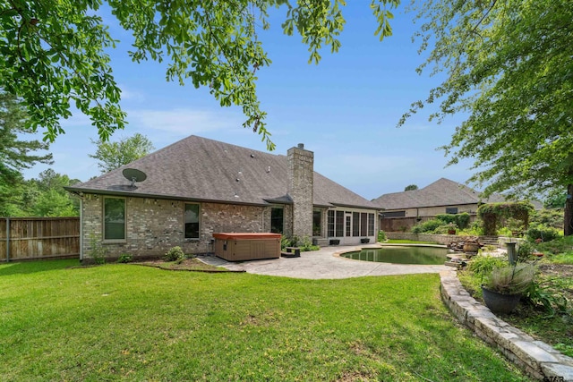 rear view of house with a yard and a hot tub