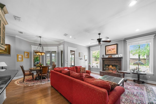 living room featuring a fireplace, ceiling fan, dark hardwood / wood-style floors, and crown molding