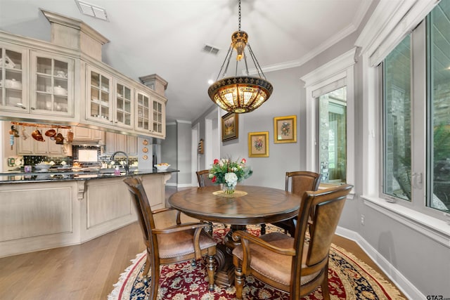 dining area with light wood-type flooring and crown molding