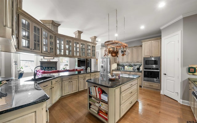 kitchen featuring ornamental molding, a kitchen island, appliances with stainless steel finishes, hardwood / wood-style floors, and kitchen peninsula