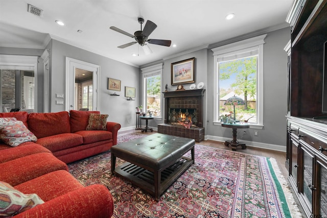 living room with ceiling fan, hardwood / wood-style flooring, crown molding, and a fireplace