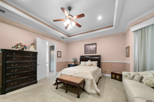 carpeted bedroom featuring connected bathroom, ornamental molding, a tray ceiling, and ceiling fan