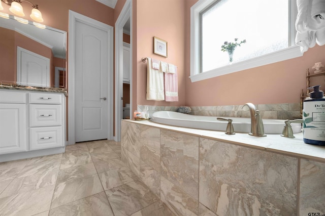 bathroom with vanity, tiled tub, and ornamental molding