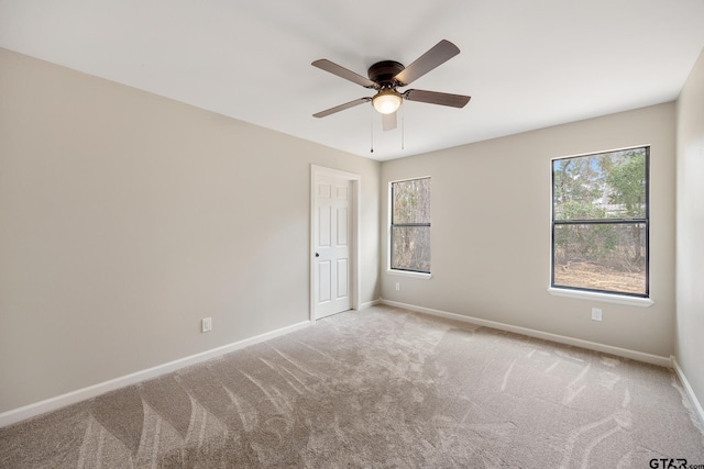 carpeted empty room featuring plenty of natural light, baseboards, and ceiling fan