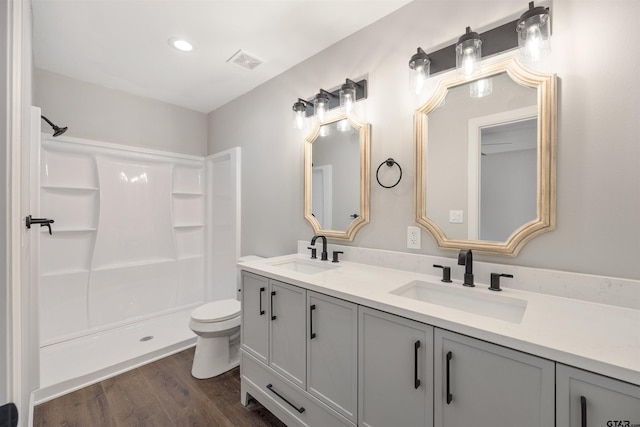 full bath with a shower, visible vents, a sink, and wood finished floors