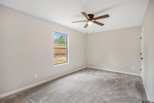 carpeted spare room featuring a ceiling fan and baseboards