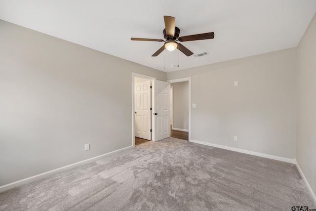 carpeted spare room with baseboards, visible vents, and a ceiling fan