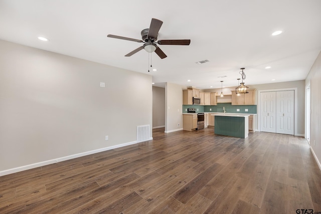 kitchen with light brown cabinets, stainless steel appliances, a kitchen island, open floor plan, and light countertops