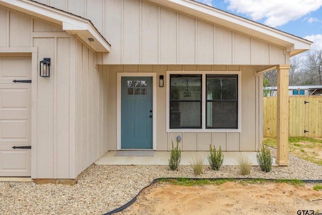 doorway to property with a garage, fence, and board and batten siding