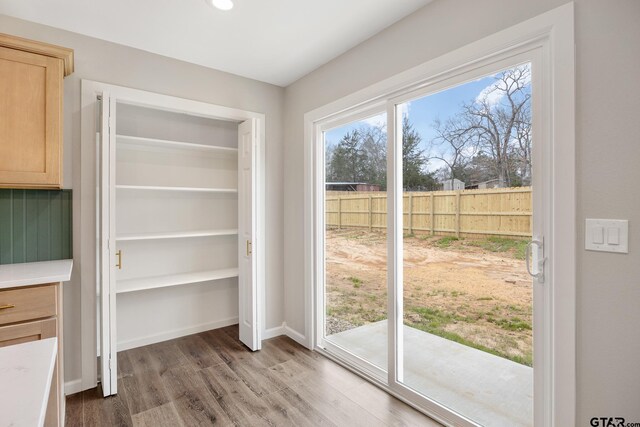 doorway featuring baseboards and wood finished floors