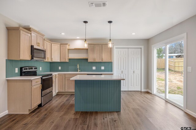 kitchen with stainless steel appliances, wood finished floors, a kitchen island, visible vents, and backsplash