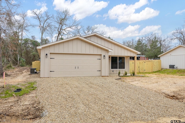 view of front of property featuring a garage, gravel driveway, central AC, and fence