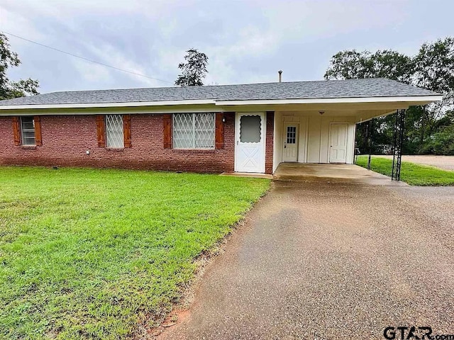 single story home featuring driveway, a carport, board and batten siding, and a front yard