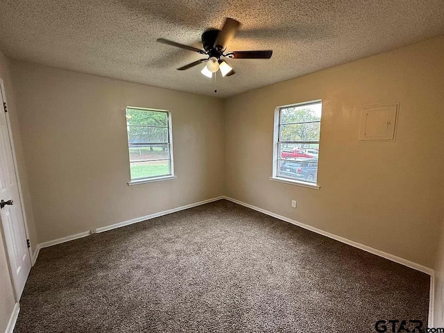 unfurnished room featuring plenty of natural light, baseboards, dark colored carpet, and a textured ceiling