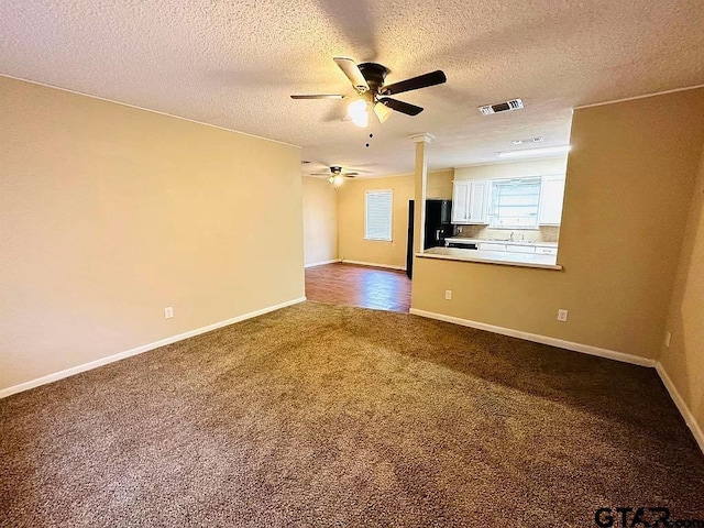 unfurnished living room with ceiling fan, baseboards, visible vents, and dark colored carpet