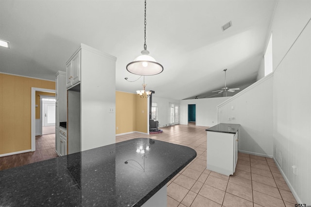 kitchen featuring lofted ceiling, white cabinetry, decorative light fixtures, light tile patterned floors, and ceiling fan with notable chandelier