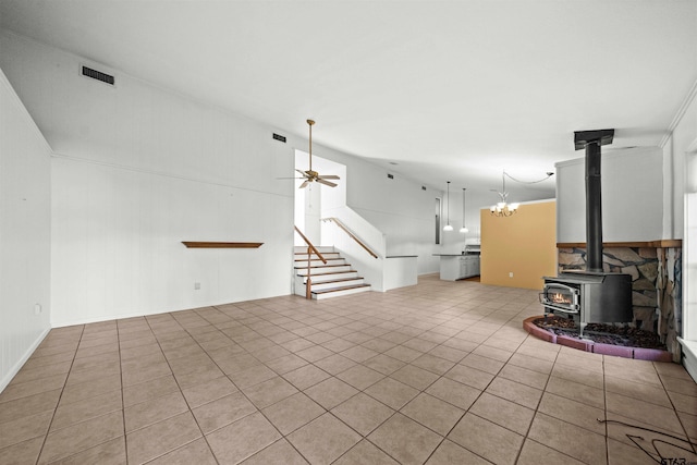 unfurnished living room with ceiling fan, light tile patterned floors, and a wood stove