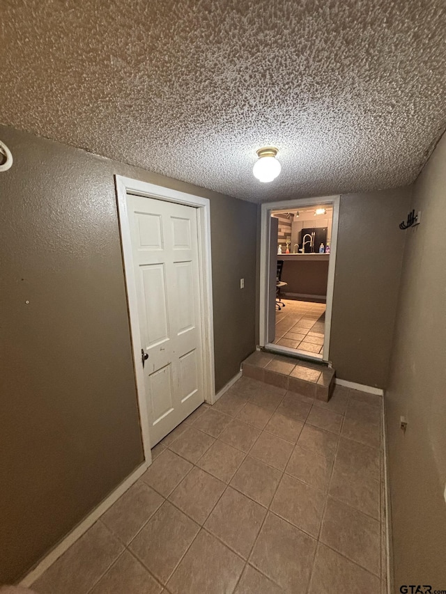 606 Glazner St, Hawkins, TX 75765 - hall featuring tile patterned floors, baseboards, a textured ceiling, and a sink