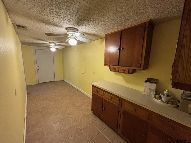 606 Glazner St, Hawkins, TX 75765 - kitchen with light countertops, a ceiling fan, a textured ceiling, brown cabinetry, and baseboards
