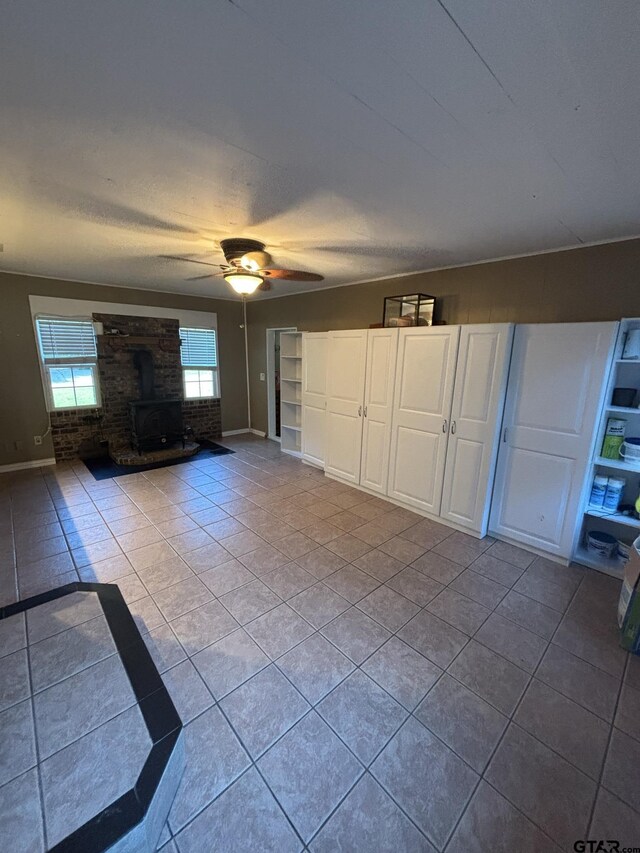 606 Glazner St, Hawkins, TX 75765 - unfurnished living room with a wood stove, tile patterned flooring, and ceiling fan