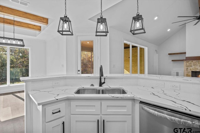 kitchen with sink, stainless steel dishwasher, a fireplace, light stone counters, and white cabinetry