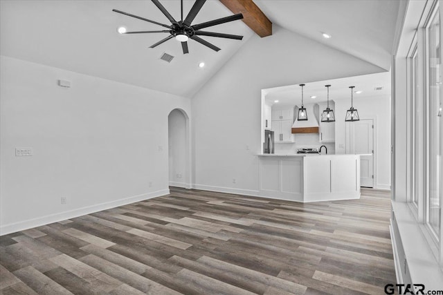 unfurnished living room featuring high vaulted ceiling, sink, ceiling fan, beam ceiling, and dark hardwood / wood-style flooring