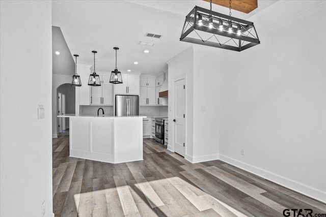 kitchen with backsplash, an island with sink, pendant lighting, white cabinets, and appliances with stainless steel finishes