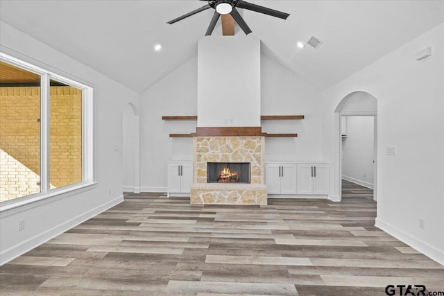 unfurnished living room featuring a fireplace, light hardwood / wood-style floors, high vaulted ceiling, and ceiling fan