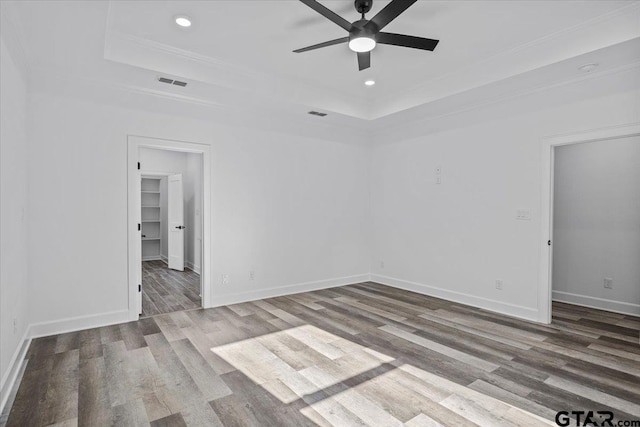 spare room with hardwood / wood-style flooring, a raised ceiling, ceiling fan, and ornamental molding