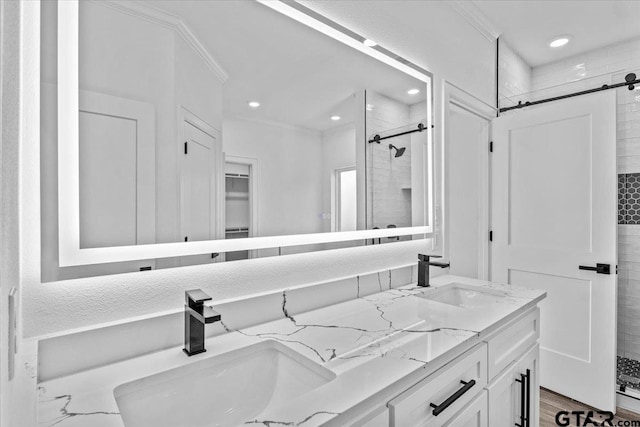 bathroom featuring a tile shower, vanity, and crown molding