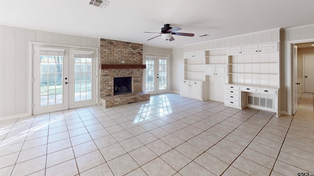 unfurnished living room with built in shelves, ceiling fan, french doors, a fireplace, and light tile patterned floors