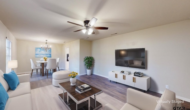 living room featuring ceiling fan with notable chandelier and light hardwood / wood-style flooring