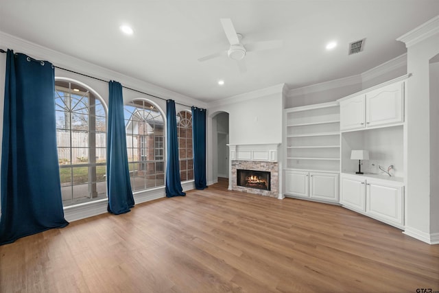 unfurnished living room with ceiling fan, a fireplace, light wood-type flooring, and ornamental molding