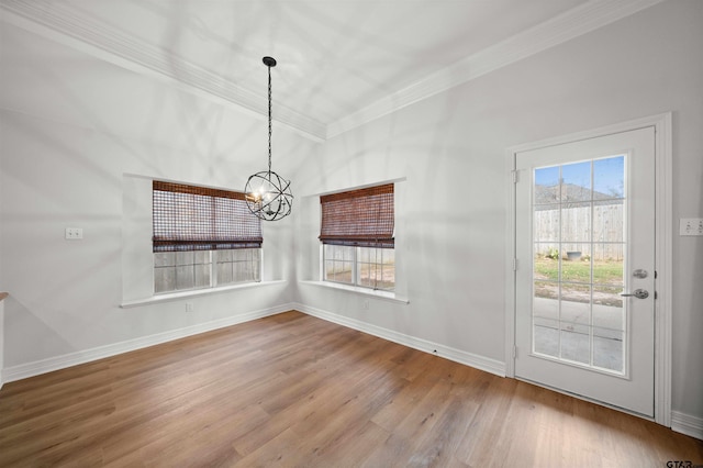 unfurnished dining area featuring hardwood / wood-style floors, crown molding, and an inviting chandelier