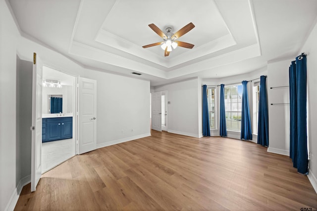 unfurnished room with a raised ceiling, ceiling fan, and light hardwood / wood-style flooring