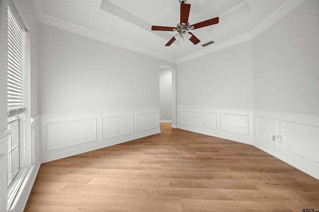 unfurnished room featuring ceiling fan, crown molding, a tray ceiling, and light hardwood / wood-style flooring