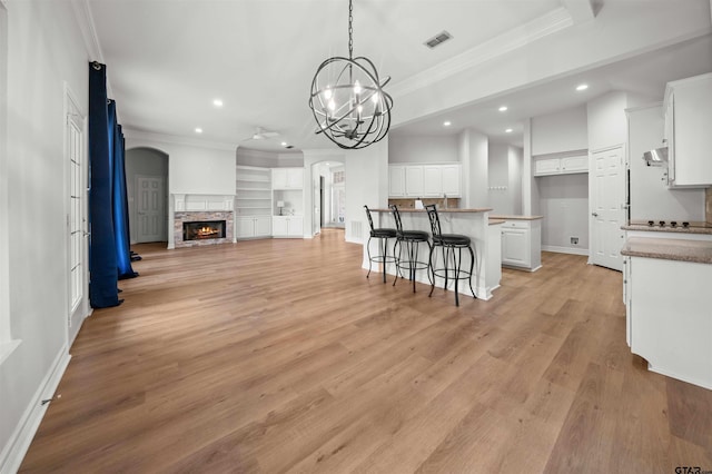 kitchen featuring white cabinetry, an inviting chandelier, built in features, a fireplace, and a kitchen island