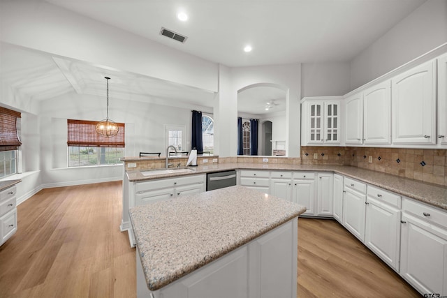 kitchen with sink, backsplash, kitchen peninsula, decorative light fixtures, and white cabinets