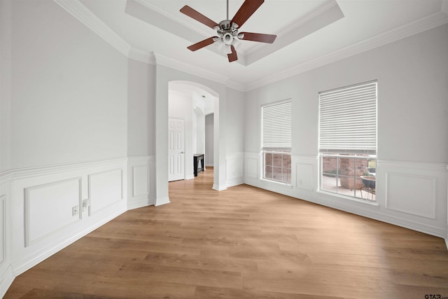 unfurnished room featuring a raised ceiling, crown molding, and light wood-type flooring